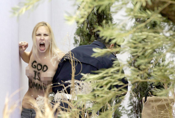 Trên ngực cô ta, được nhận dạng là  Inna Shevchenko, thủ lãnh nhóm Femen, ghi dòng chữ tiếng Anh: Chúa là đàn bà - Ảnh: AFP