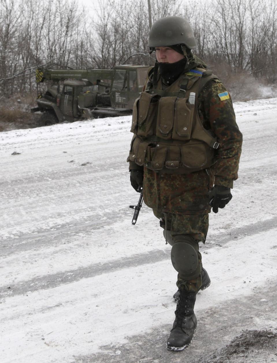 Một người lính Ukraine đi ngang qua chiếc xe tải chạy vào một con mương, gần đường giữa các thị trấn của Debaltseve và Artemivsk, Ukraine, Thứ hai 16 tháng 2, 2015