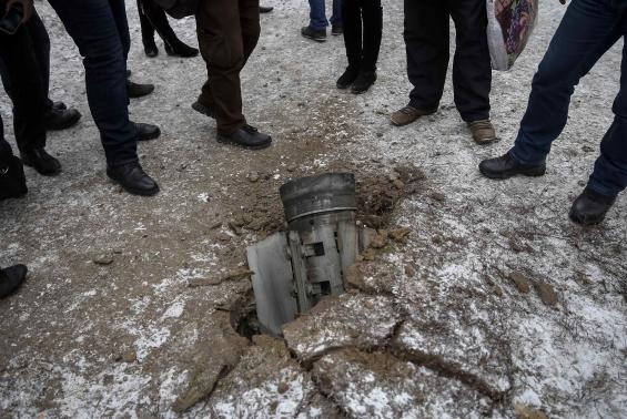 Local residents look at the remains of a rocket shell on a street in the town of Kramatorsk