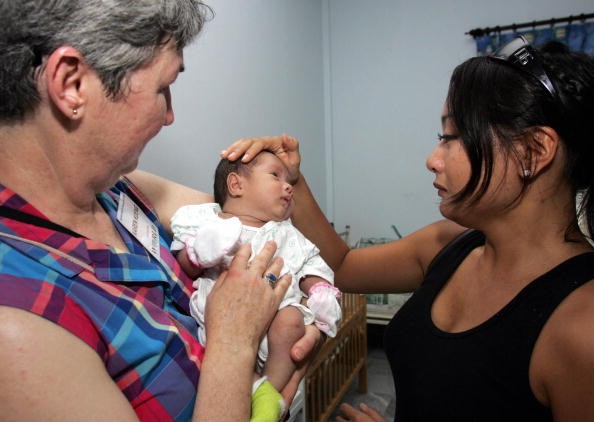 Cô Lyly Koening (phải), một trẻ Babylift, và mẹ nuôi Karen Koening thăm một trại mồ côi ở TP. HCM vào tháng 6/2005. Cô là một thành viên trong đoàn trẻ Babylift trở về thăm quê hương. Ảnh: AFP