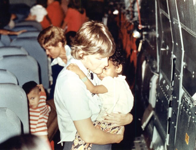 Một phụ nữ Mỹ vỗ về trẻ em trên chuyến bay rời khỏi Việt Nam. Sau đó, các em trở thành con nuôi trong các gia đình ở Mỹ, Canada, Australia và Pháp. Ảnh: DIA.mil