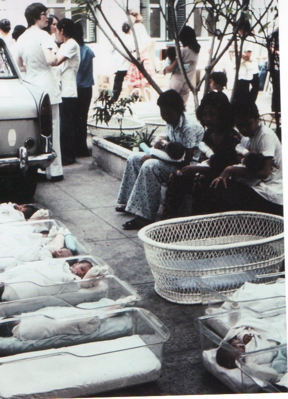 Xơ Susan (áo trắng, trái) đặt trẻ mồ côi vào lồng nhựa để chuẩn bị đưa lên máy bay.