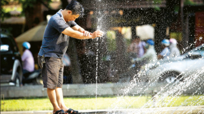 Giữa trưa hè, một người đàn ông nhờ đến vòi phun nước công cộng trên phố Quán Thánh (Hà Nội) để làm mát cơ thể - Ảnh: Nguyễn Khánh