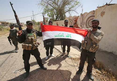 Lực lượng dân quân dòng Shiite giơ cao quốc kỳ Iraq sau khi giành lại quyền kiểm soát thành phố Baiji từ IS.