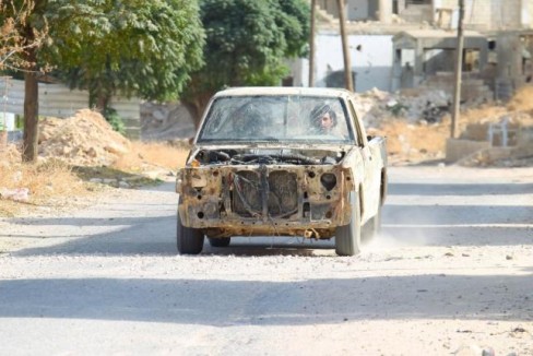 Rebel fighters drive a damaged vehicle in Latamneh city that was hit on Wednesday by Russian air strikes, in the northern countryside of Hama, Syria October 2, 2015.  REUTERS/Ammar Abdullah
