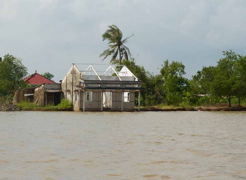 Một căn nhà sắp đổ xuống sông vì xói lở do nước dâng trên sông Gành Hào, Cà Mau. Ảnh: Hoàng Hường